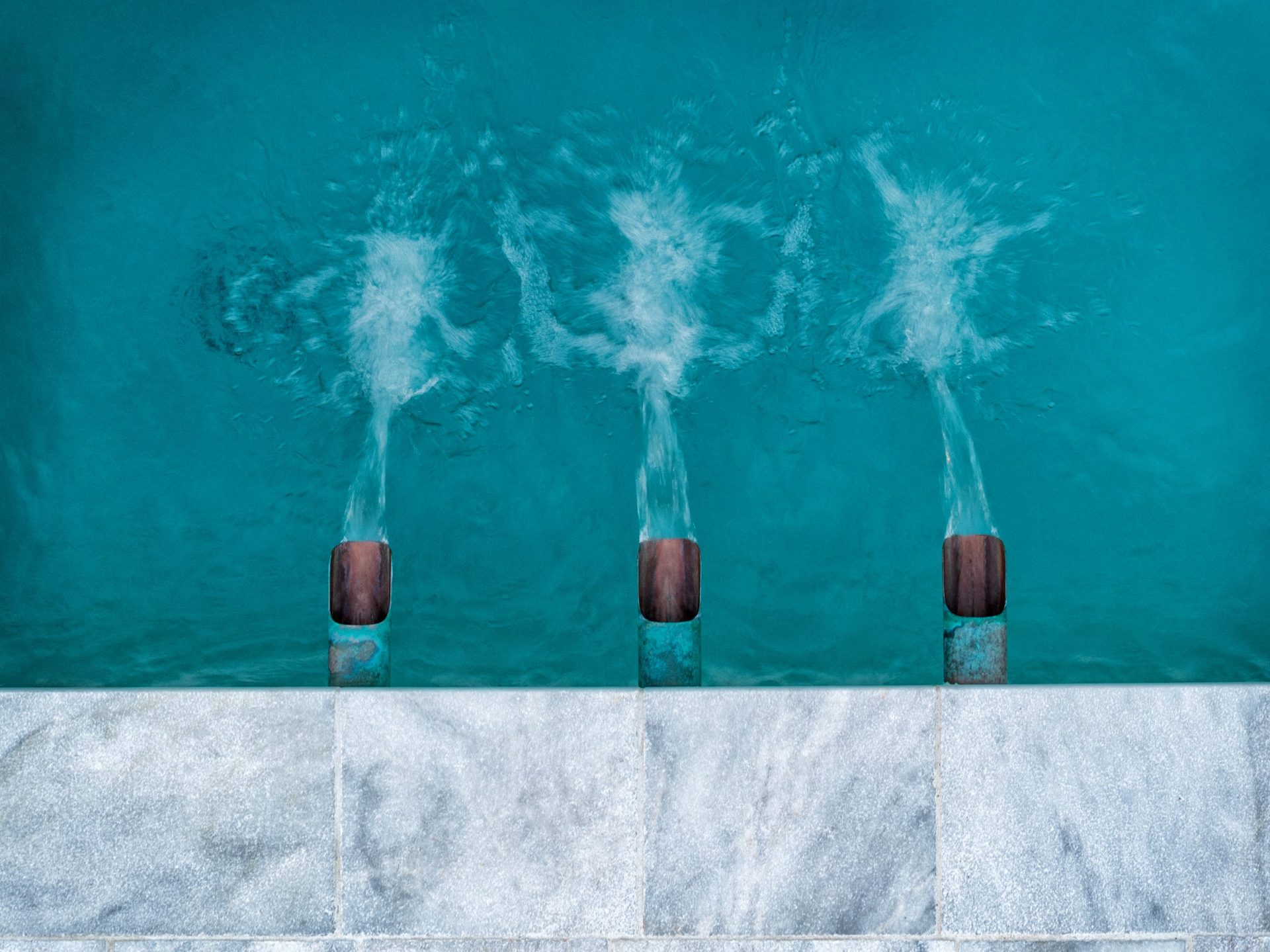 New stone coping and deck-mounted jets pouring into clear pool water